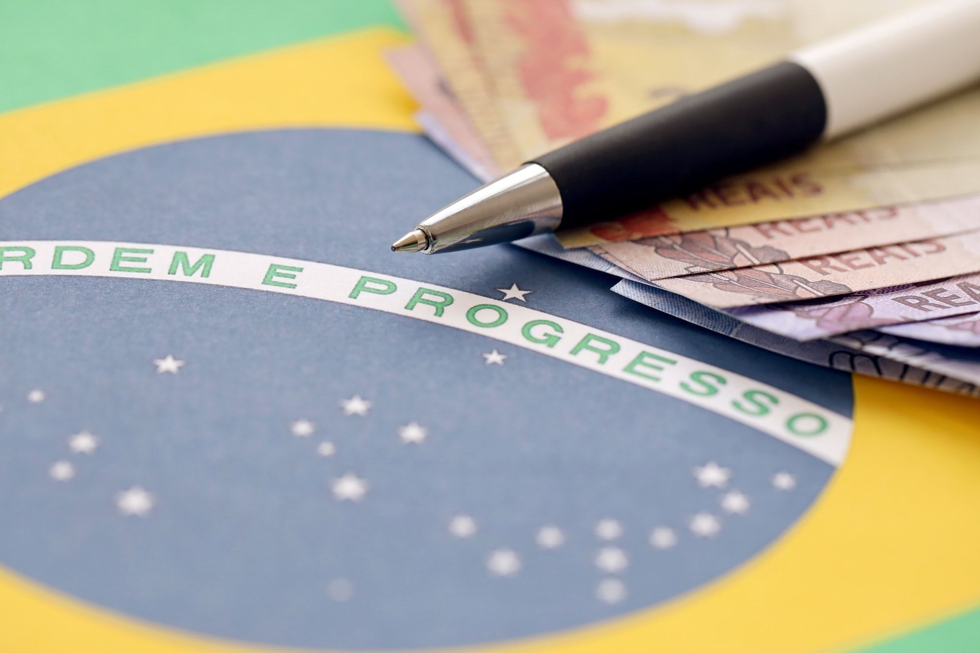 Pen With Brazilian Money Bills On Blank Of Lottery Game. Concept Of Luck And Gambling In Brazil